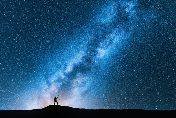 Person standing on mountain looking at stars